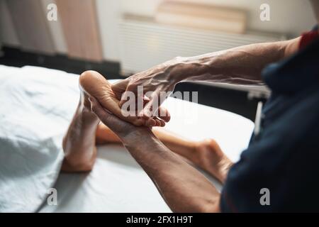 Schöne junge Frau, die auf dem Massageliegen liegt, während sie sich massiert Therapie im Spa-Salon Stockfoto