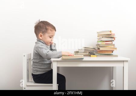 Nahaufnahme eines niedlichen kleinen Jungen, der Bücher in seinem Zimmer liest. Happy Childhood Konzept Stockfoto