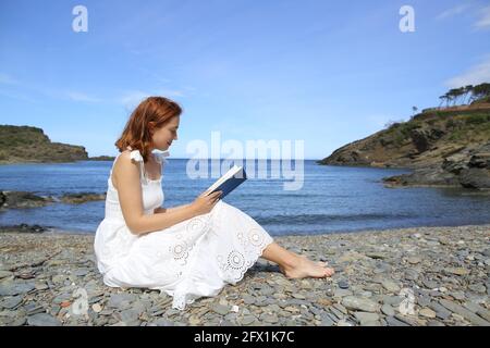 Seitenansicht Porträt einer Frau in weißem Kleid Lesung Ein Buch am Strand