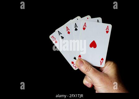 Hand mit 5 Karten, von denen vier Asse sind. Schwarzer Hintergrund Stockfoto