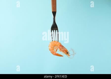 Gabel mit leckeren Garnelen auf blauem Hintergrund Stockfoto