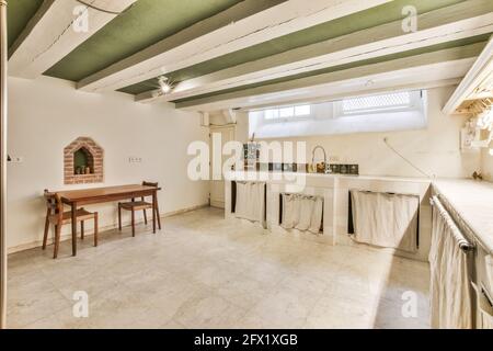 Interieur der entworfenen Küche mit weiß gefliesten Theken in alten Herrenhaus mit Balken an der Decke Stockfoto