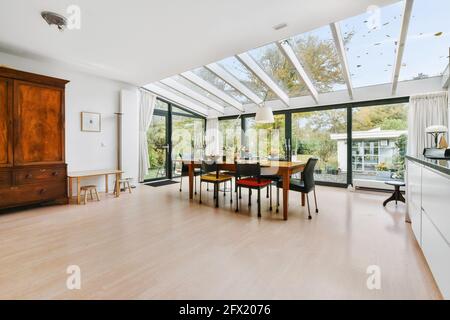 Geräumiges Herrenhaus-Küchenzimmer mit Glaswänden und Decke darüber Esstisch aus Holz bei Tageslicht Stockfoto