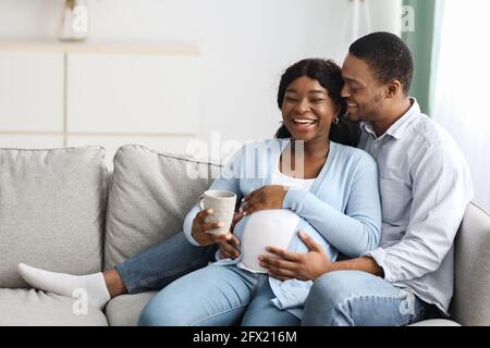 Liebevoller Ehemann küsst seine lachende, schwanger gebliebenes Weib Stockfoto