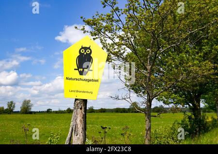 19. Mai 2021, Brandenburg, Rühstädt: Ein Schild auf einer Wiese im Storchdorf Rühstädt im Prignitz-Gebiet der UNESCO-Biosphärenreservat Elbe-Brandenburg weist auf das Naturschutzgebiet hin. Als eine der größten Storchenkolonien Mitteleuropas trägt Rühstädt den Titel „Europäisches Storchendorf“. Foto: Jens Kalaene/dpa-Zentralbild/ZB Stockfoto