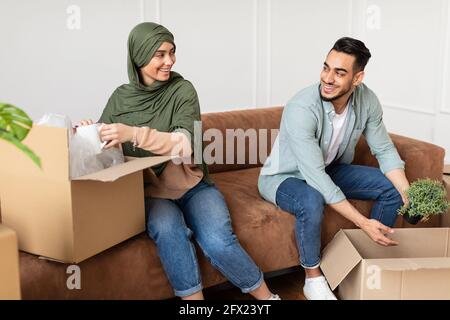 Glücklicher Mann und Frau in Hijab, die Boxen ein- oder auspacken Stockfoto