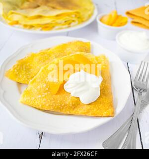 Pudding Pancakes mit Quark und Pfirsichen, garniert mit süßer Creme. Stockfoto