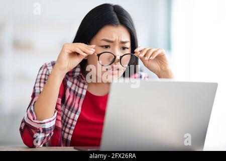 Sehstörungen. Asiatische Weibliche Abheben Brille Beim Blick Auf Laptop-Bildschirm Stockfoto