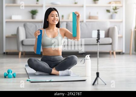 Fitness-Blogging. Junge Sportliche Asiatische Weibliche Coach Aufnahme-Tutorial Mit Widerstandsbänder Stockfoto