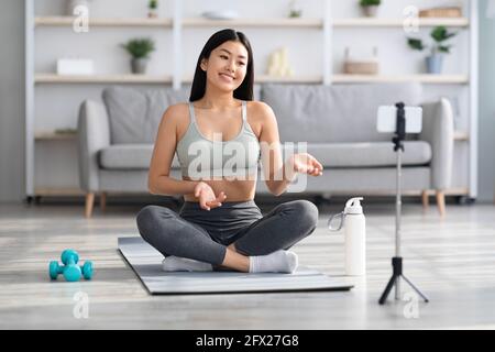 Online Yoga Konzept. Lächelnd Asiatische Weibliche Lehrer Streaming Fitness-Training Von Zu Hause Stockfoto