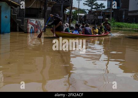 Bandung, Indonesien. Mai 2021. Am 25. Mai 2021 fahren Menschen auf einer überfluteten Straße mit dem Boot, weil der Citarum-Fluss in Bandung, West-Java, Indonesien, überschwemmt wurde. Quelle: Septianjar/Xinhua/Alamy Live News Stockfoto