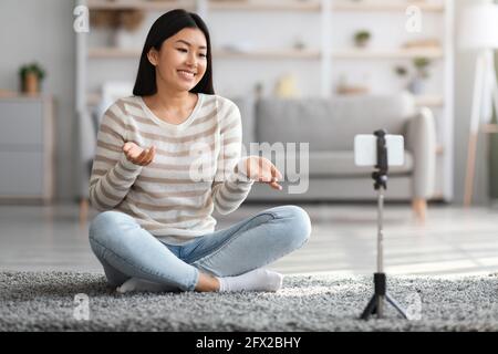Junge Asiatische Frau Mit Smartphone Auf Stativ Für Die Aufnahme Von Video Zu Hause Stockfoto