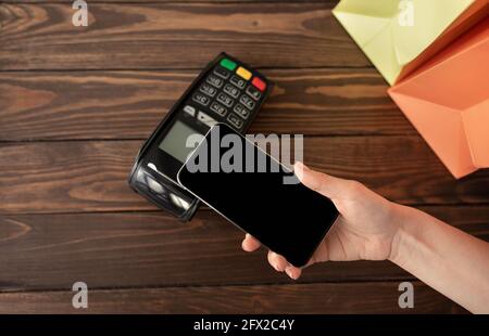 Frau, die mit der modernen easy nfc-Technologie für Einkäufe bezahlt, hält das Smartphone mit leerem Bildschirm und Nahaufnahme Stockfoto