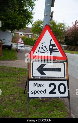 Straßenarbeiten, Rutschgefahr, Neubelag, Fahrbahn, Steinsplitter, Körnung, Kehrmaschine, Rolle, Fahrzeug, Schleudern, Rotes Warnschild, 20 mph, Höchstgeschwindigkeit, Grenzwert Stockfoto