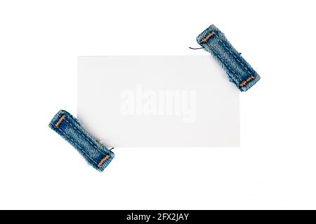 Papieretikett mit zwei Jeans-Trägern. Isolierter weißer Hintergrund Stockfoto