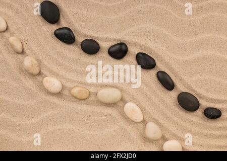 Zwei wellige Steinernen, die auf dem Sand des Strandes liegen. Draufsicht. Speicherplatz kopieren. Stockfoto