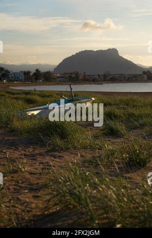 Boot im Gras auf einem Sandstrand gestrandet. Kleines weißes Boot. Es ist von Gras im Sand umgeben. Stockfoto