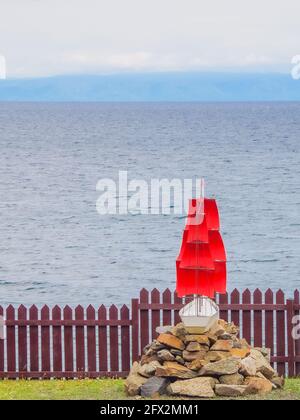Schiff hinter dem Zaun, Brigantine mit roten Segeln vor dem Hintergrund des offenen Meeres. Platz für Text kopieren, Konzept der Freiheitsbeschränkung Stockfoto