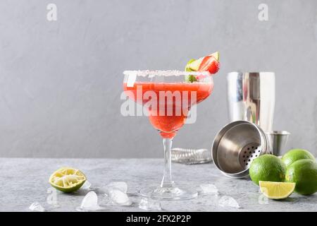 Erdbeer Margarita Cocktail garnieren Limette auf grauem Hintergrund. Alkoholischer Margarita Cocktail aus Erdbeerpüree, Limettensaft und Tequila. Stockfoto