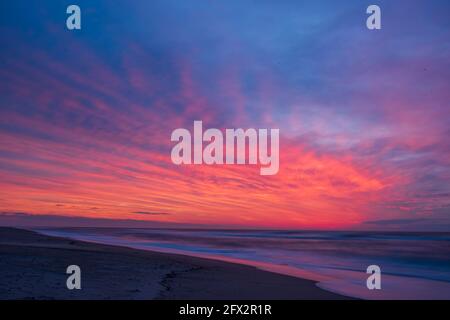 Die Momente vor dem Sonnenaufgang sind in wunderschönen rosa Farbtönen überflutet, die sich im Ozean widerspiegeln. Stockfoto