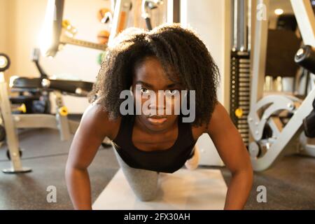Junge Frau tut Liegestütze auf Yoga-Matte. Nahaufnahme, eine Person, afroamerikanisch, schwarze Frau, afrikanisches Modell, Natürliche Haare Frau, lächelndes Gesicht, fit woma Stockfoto