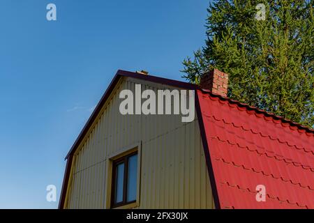 Dachgeschoss roten Dach ist aus Metall aus dem Haus mit einem Fenster. Tagsüber im Freien. Rückansicht. Stockfoto