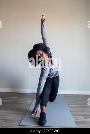 Frau praktiziert Yoga Asana im Heimstudio. Fitness Yoga, Entspannung, schwarze Frau, afroamerikanisch, natürliche Haare, Eine Person, Nahaufnahme, Stockfoto