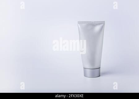 Eine Tube cremefarbener Silberfarbe auf weißem Hintergrund. Speicherplatz kopieren. Stockfoto