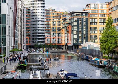 Farbenfroher Blick auf das Paddington Basin mit festgetäuten Bargen Happy People und modernen Gebäuden. Stockfoto