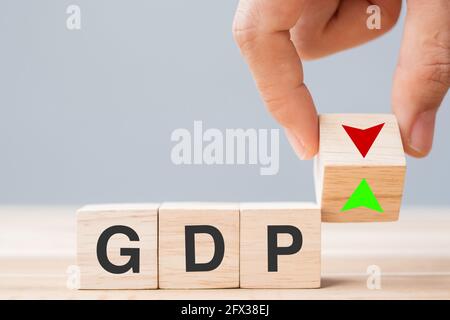 Business man Hand ändern Holz Würfel Block mit GDP Text (Bruttoinlandsprodukt) auf NACH OBEN und nach unten Pfeilsymbol Symbol. Finanzen, Management, Wirtschaft und Stockfoto