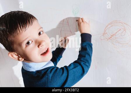 Schönes Kind zeichnet mit Buntstiften an die Wand Stockfoto