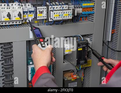 Elektriker, der mit einem Multimeter in einem Schaltschrank misst Stockfoto