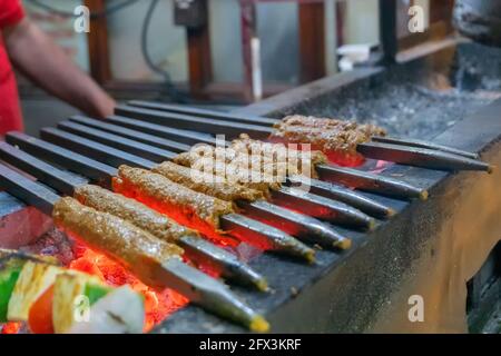 Würzige Huhn seekh Kababs werden mit Hitze in Grill mit Metallspieße gegrillt, am Abend zum Verkauf als Street Food in Old Delhi Markt. Stockfoto