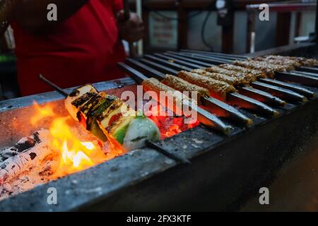 Würzige Huhn seekh Kababs werden mit Hitze in Grill mit Metallspieße gegrillt, am Abend zum Verkauf als Street Food in Old Delhi Markt. Es ist fa Stockfoto