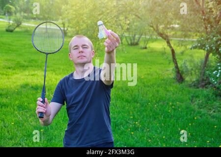 Junger Mann spielt Badminton auf dem Rasen im Park, Portrait Stockfoto