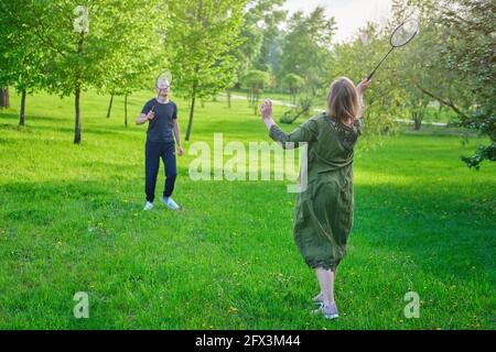 Erwachsenes Paar spielt Badminton auf dem Rasen im Park, Portrait Stockfoto
