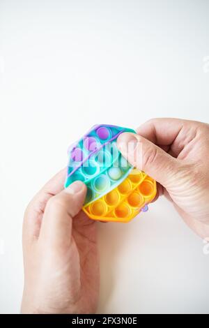 Das modischste Sinnesspielzeug. Beliebte Mode Silikon bunte Anti-Stress sechseckige Pop it Spielzeug. Jemand drückt auf ein Silikonspielzeug. Ein trendiges Spielzeug Stockfoto