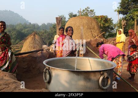 LANJIA SAORA TRIBE - Stammesfrau gießt Wasser in ein großes Gefäß mit Kunststoffrohr. Dieses Bild wurde in Puttasingh Stammesdorf von Odisha angeklickt Stockfoto