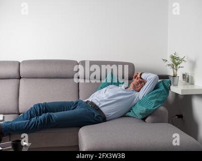 Caen, Frankreich, Mai 2021. Ein müder Mann schläft auf einem Sofa und entspannt sich, nachdem er von zu Hause aus gearbeitet hat. Stockfoto