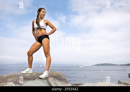 Eine Athletische Frau, Die Auf Dem Felsen Steht Und Wegschaut Stockfoto