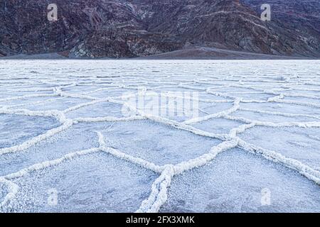 Badwater Basin at Dawn, Death Valley, Kalifornien. Berge in der Ferne; der Beckenboden ist mit weißen Salzablagerungen bedeckt. Stockfoto