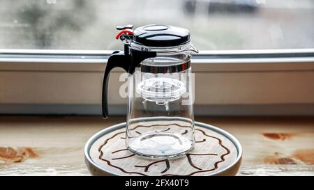 Teekannen aus Kunststoff-Glas mit Knopf und Teeflasche. Stockfoto