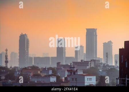 Dämmerung von Wolkenkratzern Häuser geschossen teilweise im Nebel versteckt mit dem warmen Orange der Dämmerung zeigt den Beginn eines neuen Tages in gurgaon, delhi, indien Stockfoto