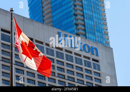 Logo oder Schild des Hilton Hotels in der Innenstadt von Toronto, Kanada. Vor dem berühmten Platz winkt eine Maple Leaf-Flagge Stockfoto