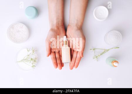 Frau mit Flasche Creme über Tabelle mit kosmetischen Produkten Stockfoto