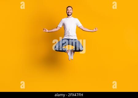In voller Länge Körpergröße Foto von springenden Mann lächelnd tun Yoga-Übungen Asana isoliert lebendige gelbe Farbe Hintergrund Stockfoto