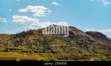 Typische Landschaft Madagaskars - grüne und gelbe Reisterrassenfelder Auf kleinen Hügeln mit Lehmhäusern in der Region bei Ambositra Stockfoto