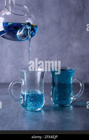 Teekannen blau Thai Gießen Tee in eine Tasse auf grau Hintergrund Stockfoto