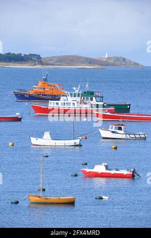 Ein ruhiger, sonniger Blick am späten Nachmittag auf das Rettungsboot und die Touristenfähre im Hafen von Hugh Town, St. Mary's, Isles of Scilly, mit der Round Island Stockfoto