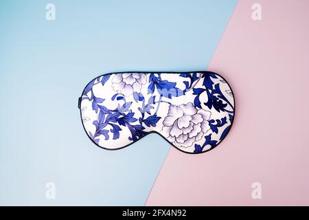 Schöne Seide Schlafmaske für die Augen mit Blumenmuster auf einem geometrischen rosa blauen Hintergrund Stockfoto